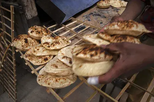 A worker collects Egyptian traditional 'baladi' flatbread, at a bakery, in el-Sharabia, Shubra district, Cairo, Egypt, Wednesday, March 2, 2022. The Russian tanks and missiles besieging Ukraine also are threatening the food supply and livelihoods of people in Europe, Africa and Asia who rely on the vast, fertile farmlands of the Black Sea region. That could create food insecurity and throw more people into poverty in places like Egypt and Lebanon, where diets are dominated by government-subsidiz