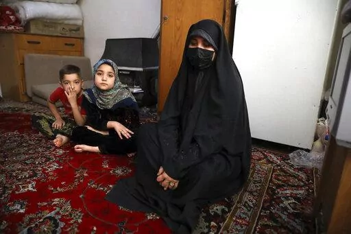 Afghan refugee Zahra Husseini and her children Salehe, center, and Shahrzad sit in their room in a poor suburb of Tehran, Iran, April 21, 2022. The Taliban members who killed her activist husband offered Husseini a deal: Marry one of us, and you'll be safe. Husseini, 31, decided to flee to Iran. (AP Photo/Vahid Salemi)