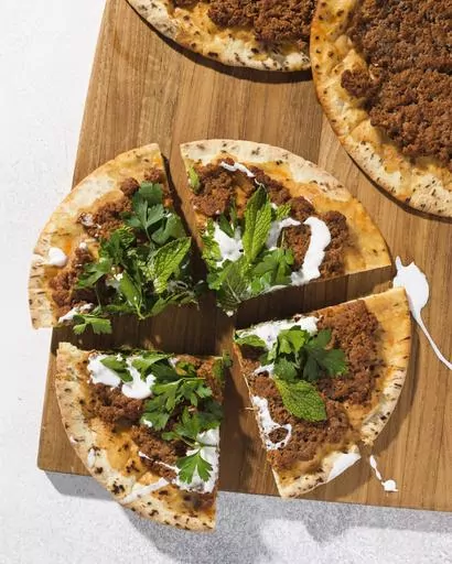 This image released by Milk Street shows a recipe for lahmajoun, a flatbread topped with spiced ground lamb, tomatoes and bell pepper. (Milk Street via AP)