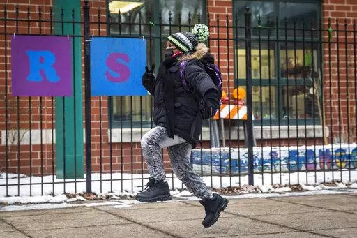A student skips as they arrive at Jordan Community Public School in Rogers Park on the North Side, Wednesday,  Jan. 12, 2022 in Chicago. Students returned to in-person learning Wednesday after a week away while the Chicago Public Schools district and the Chicago Teachers Union negotiated stronger COVID-19 protections. (Ashlee Rezin /Chicago Sun-Times via AP)