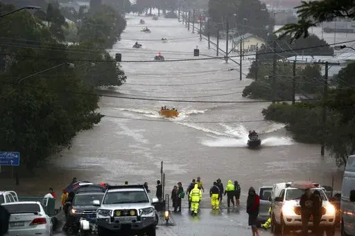 People use small boats to travel through flood water in Lismore, Australia, Monday, Feb. 28, 2022. Heavy rain is bringing record flooding to some east coast areas and claimed seven lives while the flooding in Brisbane, a population of 2.6 million, and its surrounds is the worst since 2011 when the city was inundated by what was described as a once-in-a-century event. (Jason O'Brien/AAP Image via AP)