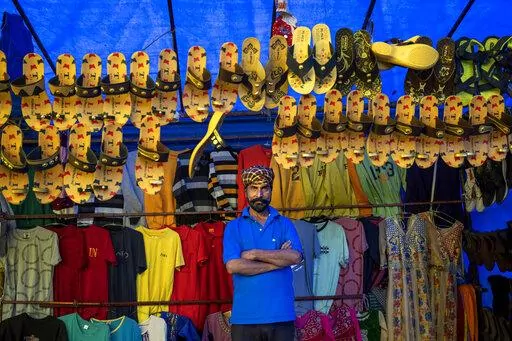 Prem Singh, who travelled from Hoshiarpur in Punjab, sells footwear and clothes at his stall at a local fair in Dharmsala, India, Sunday, Sept. 4, 2022. In small north Indian towns, some enterprising men and women move from place to place with bags full of colorful wares to sell at local fairs, keeping centuries-old traditions alive when roving fairs were the main vehicle of commerce. (AP Photo/Ashwini Bhatia)