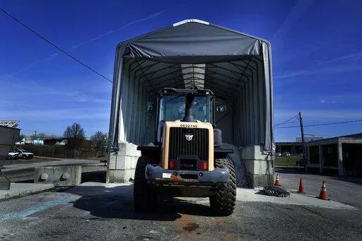 A tractor sits in front of a pile of salt used to create a brine that will help clear road of ice and snow ahead of a winter storm at the GDOT's Maintenance Activities Unit location on Friday, Jan. 14, 2022, in Forest Park, Ga. A winter storm is headed south that could effect much of Georgia through Sunday. (AP Photo/Brynn Anderson)