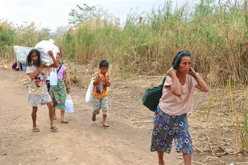 Displaced people from Myanmar carry donated lunch boxes to their tents along the Thai side of the Moei River in Mae Sot, Thailand on Feb. 5, 2022. Thailand has sent thousands of people fleeing escalating violence by Myanmar’s military back home despite the risk to their lives, and despite international refugee laws that forbid the return of people to countries where their lives may be in danger. They are now living in limbo, forced to ricochet between both sides of the river dividing the two c
