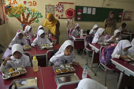 Students have their meals during the kick off of President Prabowo Subianto's ambitious free meal program to feed children and pregnant women nationwide despite critics saying that its required logistics could hurt Indonesia's state finances and economy, at an elementary school in Depok, West Java, Indonesia, Monday, Jan. 6, 2025. (AP Photo/Dita Alangkara)