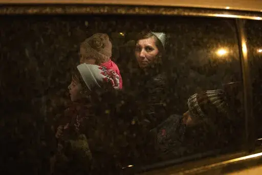A woman from Ukraine with her children sit in a car belonging to a volunteer, to take them to a hostel after arriving at Keleti station in Budapest, Hungary, on Friday, March 18, 2022. (AP Photo/Anna Szilagyi)