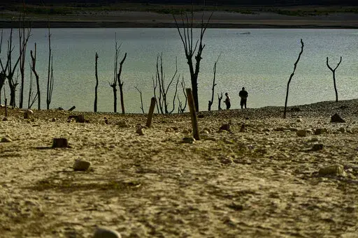 People walk close to the border at Yesa's reservoir affected by drought, on a sunny summer day in Yesa, around 55 kilometers (34,17 miles), from Pamplona, northern Spain, Sept. 14, 2022. Widespread drought that dried up large parts of Europe, the United States and China this past summer was made 20 times more likely by climate change, according to a new study. (AP Photo/Alvaro Barrientos)
