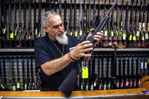 Salesman John Licata demonstrates a competition shooting gun at SP firearms on Thursday, June 23, 2022, in Hempstead, New York. (AP Photo/Brittainy Newman)