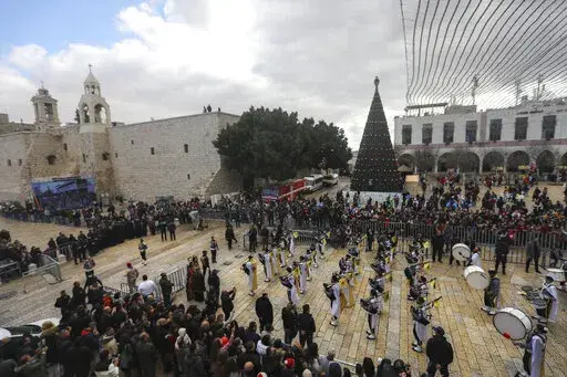 Palestinian scout bands parade through Manger Square at the Church of the Nativity, traditionally believed to be the birthplace of Jesus Christ, during Christmas celebrations, in the West Bank town of Bethlehem, Friday, Dec. 24, 2021. The biblical town of Bethlehem is gearing up for its second straight Christmas Eve hit by the coronavirus with small crowds and gray, gloomy weather dampening celebrations Friday in the traditional birthplace of Jesus. (AP Photo/Mahmoud Illean)