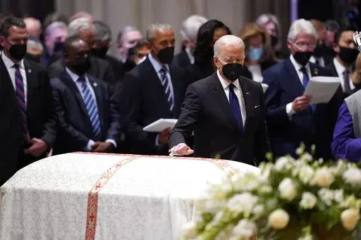 President Joe Biden places his hand on the casket of former Secretary of State Madeleine Albright during the funeral service at the Washington National Cathedral, Wednesday, April 27, 2022, in Washington. (AP Photo/Evan Vucci)