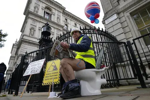 An activist sits on a toilet at the entrance to Downing Street to protest against raw sewage dumping in the rivers and seas around the UK in London, on Oct. 26, 2021. EU lawmakers have a new, post-Brexit reason to be annoyed with Britain: British sewage overflows seeping into the English Channel and North Sea. (AP Photo/Frank Augstein)