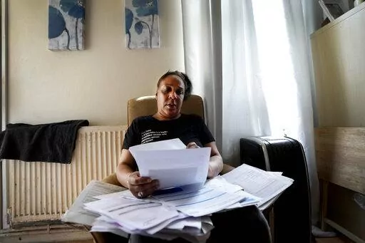 Jennifer Jones sorts her bills at her small flat in London, Thursday, Aug. 25, 2022. Like millions of people, Jones, 54, is struggling to cope as energy and food prices skyrocket during Britain's worst cost-of-living crisis in a generation. The former school supervisor has health problems and relies on government benefits to get by, but her welfare payments are nowhere near enough to cover her sharply rising bills.  (AP Photo/Frank Augstein)