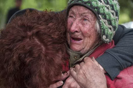 Tetiana, 82, cries with her daughter as she is evacuated from Vovchansk, Ukraine, Saturday, May 11, 2024. Her husband was killed in their house after a Russian airstrike on the city. (AP Photo/Evgeniy Maloletka)