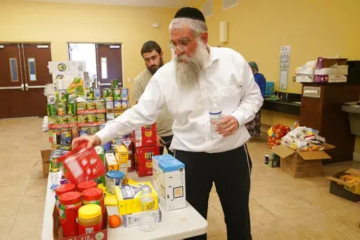 Rabbi Yitzchok Minkowicz supervises the pantry inside the Chabad Lubavitch of Southwest Florida, Monday, Oct. 3, 2022, in Fort Myers, Fla. The synagogue has been transformed into a full-fledged community center with food trucks and a pantry. They plan on celebrating Yom Kippur on Tuesday. (AP Photo/Marta Lavandier)