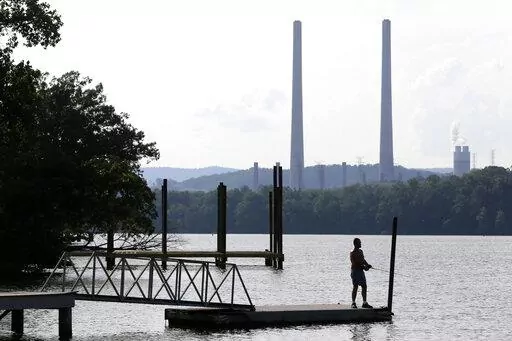 In this Aug. 7, 2019, file photo, a man fishes at William B. Ladd Park near the Kingston Fossil Plant in Kingston, Tenn. The largest public power company in the U.S. is launching a program to develop and fund new small modular nuclear reactors as part of its strategy to dramatically reduce greenhouse gas emissions. The board for the Tennessee Valley Authority on Thursday, Feb. 10, 2022 authorized the program to assess moving forward with new nuclear technology, with up to $200 million to be spen