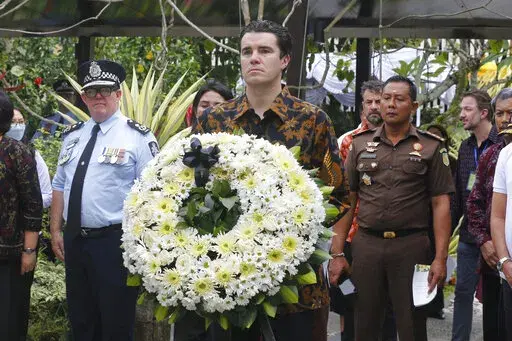 Australian Assistant Minister for Foreign Affairs Tim Watts, center, carries a wreath during the commemoration of the 20th anniversary of the Bali bombing that killed 202 people, mostly foreign tourists, including 88 Australians and seven Americans, at the Australian Consulate in Denpasar, Bali, Indonesia on Wednesday, Oct. 12, 2022. Services were held simultaneously in several places in Australia and at Bali's Australian Consulate in the city of Denpasar, where Australian survivors and relative
