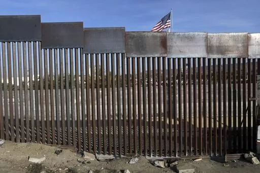 A United States flag flies behind the border fence that divides Mexico and the U.S., in Tijuana, Mexico, Nov. 21, 2018. Nearly a thousand migrants that recently crossed from Guatemala into Mexico formed a group Saturday, July 15, 2023, to head north together in hopes of reaching the border with the United States. (AP Photo/Rodrigo Abd, File)