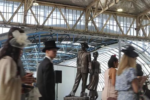 People bound for Royal Ascot race meeting walk past the National Windrush Monument in Waterloo Station in London, Thursday June 22, 2023. Windrush Day is being marked on Thursday on what is the 75th anniversary of the arrival of the ship the Empire Windrush on June 22, 1948. It became a symbol of the post-war migration that transformed the U.K. and its culture. The term Windrush generation has come to stand for hundreds of thousands of people who arrived in the U.K. between the late 1940s and ea