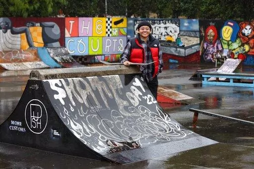 Sara Campos poses at tennis courts being converted to a skatepark at Portland State University in Portland, Ore., Friday, Oct. 28, 2022. Campos is a fellow in Tony Hawk's The Skatepark Project program, which is training 15 skateboarding enthusiasts in community organizing and project management so they can build a skatepark in their neighborhoods. (AP Photo/Steve Dipaola)