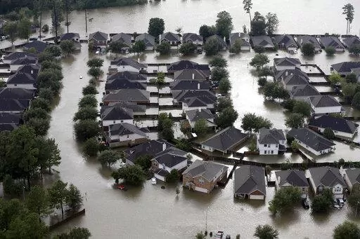 Homes are surrounded by floodwaters from Tropical Storm Harvey in Spring, Texas, Tuesday, Aug. 29, 2017. Experts say more intense storms driven by climate change are boosting contamination risks for privately-owned drinking water wells. (AP Photo/David J. Phillip, File)