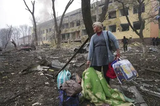A woman walks outside the damaged by shelling maternity hospital in Mariupol, Ukraine, Wednesday, March 9, 2022. A Russian attack has severely damaged a maternity hospital in the besieged port city of Mariupol, Ukrainian officials say. (AP Photo/Evgeniy Maloletka)