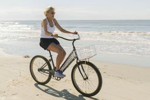 First lady Jill Biden rides a bicycle along the beach at Kiawah Island, S.C., Aug. 14, 2022. Jill Biden says exercise helps her find ‘inner strength.’ The first lady attends spin classes when she's on the road. She rides a bicycle near her Delaware beach home. She jogs on the White House driveway. Biden also takes barre classes and rides a Peloton bike. (AP Photo/Manuel Balce Ceneta, File)