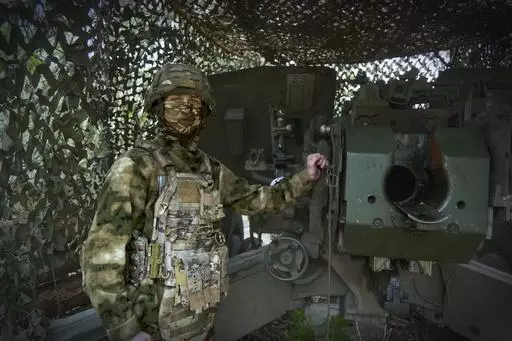 In this photo taken on Friday, April 26, 2024 and released by the Russian Defense Ministry Press Service, a Russian soldier poses for a photo next to a 2A65 "Msta-B" howitzer at a position in an undisclosed location in Ukraine. (Russian Defense Ministry Press Service via AP)