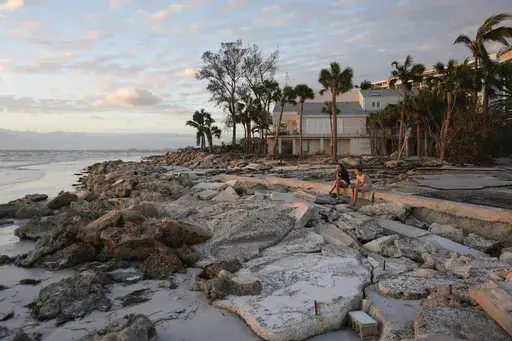 Young people from Sarasota, Fla., visit a familiar beach on Siesta Key, Fla., which they say was already decimated by Hurricane Helene, and lost feet more of sand coverage in Hurricane Milton, Thursday, Oct. 10, 2024. (AP Photo/Rebecca Blackwell)