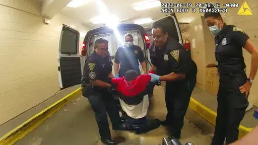In this image taken from police body camera video provided by New Haven Police, Richard "Randy" Cox, center, is pulled from the back of a police van and placed in a wheelchair after being detained by New Haven Police on June 19, 2022, in New Haven, Conn. Five Connecticut police officers were charged with misdemeanors Monday, Nov. 28, over their treatment of Cox after he was paralyzed from the chest down in the back of a police van. (New Haven Police via AP, File)