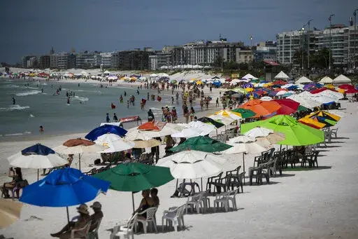 Beachgoers congregate on Fort Beach in Cabo Frio, Brazil, Wednesday, Dec. 15, 2021. G.A.S Consulting & Technology, a cryptocurrency investment firm founded by Glaidson Acacio dos Santos, a former waiter-turned-multimillionaire who is the central figure in what is alleged to be one of Brazil’s biggest-ever pyramid schemes, was based in the beach town dos Santos called home. (AP Photo/Bruna Prado)