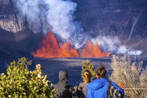 In this photo provided by the National Park Service, people watch as an eruption takes place on the summit of the Kilauea volcano in Hawaii, Monday, Dec. 23, 2024. (Janice Wei/NPS via AP)