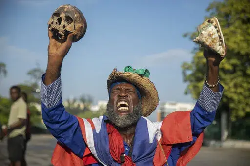 A protester holding up a skull and seashell shouts for the resignation of Haitian Prime Minister Ariel Henry in the street in the Champs de Mars area where the prime minister attended a ceremony marking the death anniversary of revolutionary leader Jean-Jacques Dessalines in Port-au-Prince, Haiti, Monday, Oct. 17, 2022. (AP Photo/Odelyn Joseph)