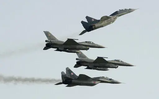 Two Polish Air Force Russian made Mig 29's fly above and below two Polish Air Force U.S. made F-16's fighter jets during the Air Show in Radom, Poland, on Aug. 27, 2011. In a private video call with American lawmakers over the weekend, Ukrainian President Volodymyr Zelenskyy made a “desperate” plea to the United States to help Kyiv get more warplanes to fight Russia's invasion and retain control of its airspace. (AP Photo/Alik Keplicz, File)