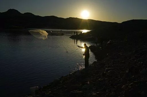 A fisherman throws a cast net along shore of Lake Mead at the Lake Mead National Recreation Area, Friday, Jan. 27, 2023, near Boulder City, Nev. Six western states that rely on water from the Colorado River have agreed on a plan to dramatically cut their use. California, the state with the largest allocation of water from the river, is the holdout. (AP Photo/John Locher)