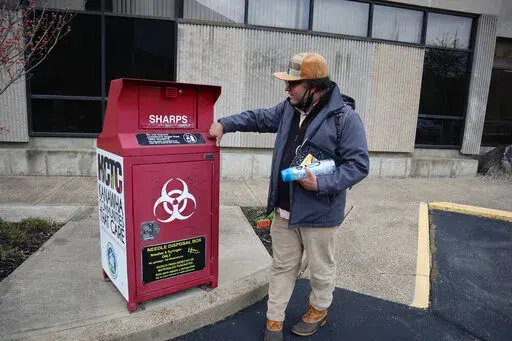Joe Solomon, Democratic candidate for city council and co-director of the non-profit Solutions Oriented Addiction Response, stops by a syringe disposal box outside the Kanawha-Charleston Health Department, Tuesday, April 5, 2022, in Charleston, W.Va. Solomon had spent three days eating at soup kitchens and sleeping under bridges and in parking lots while interviewing residents about the changes they’d like to see in the city’s response to issues like homelessness and substance use. (AP Photo