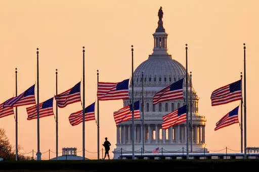Lowered to half-staff in honor of former Senate Majority Leader Bob Dole of Kansas, flags fly in the breeze at sunrise on the National Mall with the U.S. Capitol in the background, Monday, Dec. 6, 2021, in Washington. (AP Photo/J. David Ake)