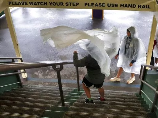 A gust of window blows a guest's rain poncho on the ferry boat on the way to the Magic Kingdom at Walt Disney World in Lake Buena Vista, Fla., Wednesday, Nov. 9, 2022, as conditions deteriorate with the approach of Hurricane Nicole. All 4 Disney parks in Central Florida closed early Wednesday because of the impending storm. (Joe Burbank/Orlando Sentinel via AP)