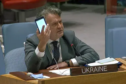 In this image from UNTV video, Ukraine's Ambassador to the United Nations Sergiy Kyslytsya, holds up a phone as he speaks an emergency meeting of the U.N. Security Council Wednesday, Feb. 23, 2022, at U.N. headquarters. (UNTV via AP)