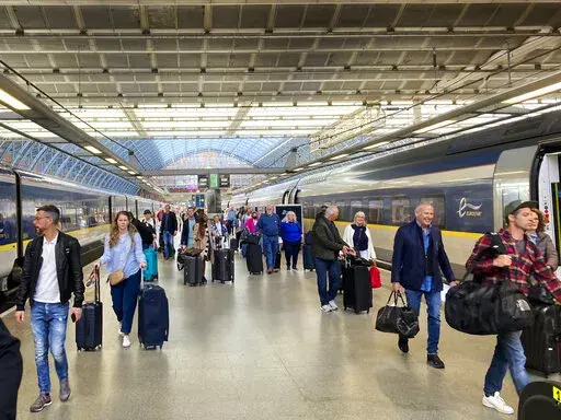 Travelers at St. Pancras International train station board the high speed Eurostar train to Paris, in London, Saturday, May 21, 2022. The World Economic Forum is encouraging European attendees to come to its exclusive gathering in the Swiss Alps by train. Its part of efforts to burnish the sustainability credentials for an event in Davos that conjures up up images of government leaders, billionaire elites and corporate titans jetting in on carbon-spewing private planes. (AP Photo/Kelvin Chan)