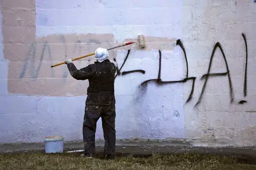 A worker paints over graffiti saying 'Yes to Peace!' on a wall of an apartment building in St. Petersburg, Russia, Friday, March 18, 2022. (AP Photo, File)