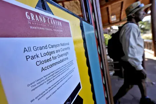 A sign denoting park lodge closures hangs on the door as a guest exits the Bright Angel Lodge, Thursday, Aug. 29, 2024, in Grand Canyon, Ariz. (AP Photo/Matt York)