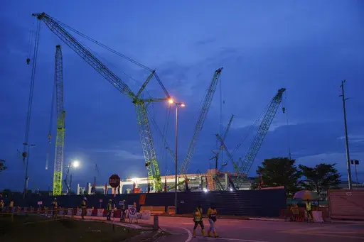 Construction workers walk outside a data center building under construction in Johor Bahru town at Johor state, Saturday, Sept. 28, 2024. (AP Photo/Vincent Thian)