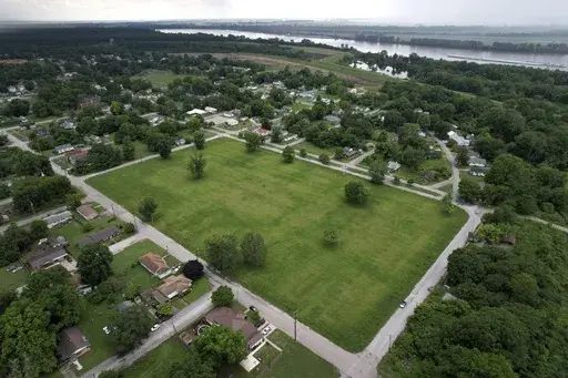 A vacant lot where, until recently, residences stood as a levee stands and Mississippi River flows past in the distance Thursday, May 23, 2024, in Cairo, Ill. Devastating flooding, driven in part by climate change, is taking an especially damaging toll on communities that once thrived along the banks of the river. (AP Photo/Jeff Roberson)