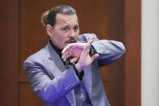 Actor Johnny Depp demonstrates how he claims to have shielded himself from an alleged attack by his ex-wife Amber Heard, as he testifies during the trial at the Fairfax County Circuit Court in Fairfax, Va., Wednesday, April 20, 2022. Actor Johnny Depp sued his ex-wife Amber Heard for libel in Fairfax County Circuit Court after she wrote an op-ed piece in The Washington Post in 2018 referring to herself as a "public figure representing domestic abuse." (Evelyn Hockstein/Pool via AP)