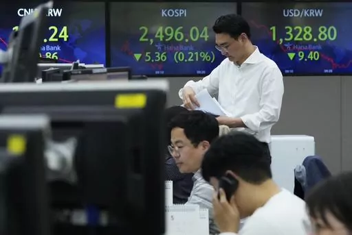 A currency trader works near the screens showing the Korea Composite Stock Price Index (KOSPI), top center, and the foreign exchange rate between U.S. dollar and South Korean won, top right, at the foreign exchange dealing room of the KEB Hana Bank headquarters in Seoul, South Korea, Thursday, May 4, 2023. Markets: Asian stock markets were mixed Thursday after the Federal Reserve raised its benchmark lending rate again to cool inflation and said it isn't sure what may come next. (AP Photo/Ahn Yo
