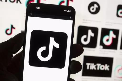 The TikTok logo is displayed on a mobile phone in front of a computer screen, Oct. 14, 2022, in Boston. On Tuesday, May 7, 2024, TikTok and its Chinese parent company ByteDance filed suit against the U.S. federal government to challenge a law that would force the sale of ByteDance's stake or face a ban, saying that the law is unconstitutional. (AP Photo/Michael Dwyer, File)