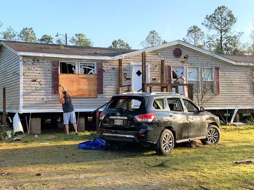 Terry Watson measures a window in his in-law's house for plywood after a tornado on Wednesday, blew out the windows in the home and his wife's SUV parked out front in Vancleave, Miss., on Thursday, March 31, 2022. A line of severe storms packing isolated tornadoes and high winds ripped across the Deep South overnight,  toppling trees and power lines and leaving homes and businesses damaged as the vast weather front raced across several states. (Mary Perez /The Sun Herald via AP)
