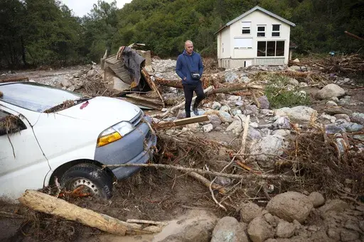 A man walks among a destroyed car and homes following a flooding in Buturovic Polje, Bosnia, Sunday, Oct. 6, 2024. (AP Photo/Armin Durgut)
