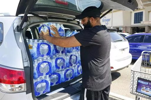 Rajwinder Singh, a gas station/convenience store owner, pats into place the 15 cases of drinking water he purchased from a Kroger grocery store into his vehicle, Tuesday, Aug. 30, 2022, in Jackson, Miss. Parts of Jackson were without running water Tuesday because recent flooding worsened problems in one of two water-treatment plants as part of the city's response to longstanding water system problems. The state Health Department put Mississippi's capital city under a boil-water notice in late Ju