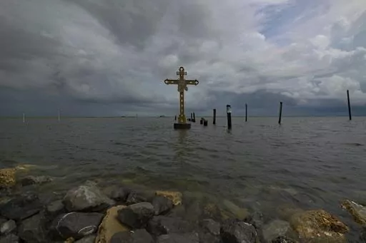 A cross erected on Shell Beach as a memorial to the residents in St. Bernard Parish, La. who died after Hurricane Katrina in 2005 is visible before Hurricane Ida makes landfall in New Orleans, Aug. 28, 2021. Hurricanes in the U.S. over last few decades killed thousands more people than meteorologists traditionally calculate and a disproportionate number of those victims are poor, vulnerable and minorities, according to a new epidemiological study released Wednesday, Aug. 16, 2023. (AP Photo/Matt